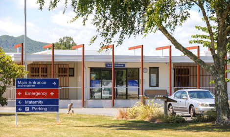 White hospital building with sign with directions.